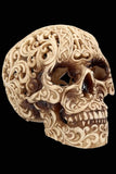 An intricately carved decorative skull sculpture with ornate scrollwork patterns, shown against a plain white background.